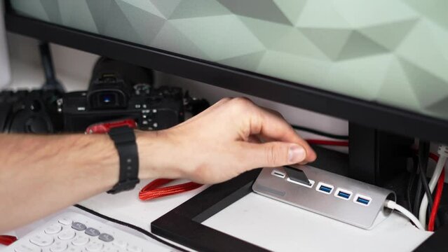 A man inserts an sd card into a card reader and saves photos to a PC. Close-up of hands and slow motion.
