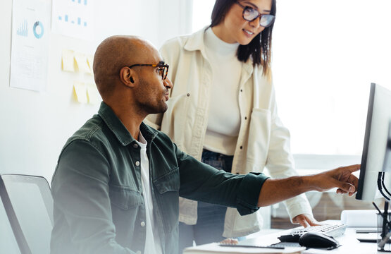 Software developer using a computer and having a discussion with his manager