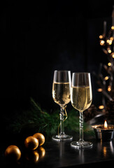 Template for holiday party invitation with two glasses of champagne on New Year's table on black.