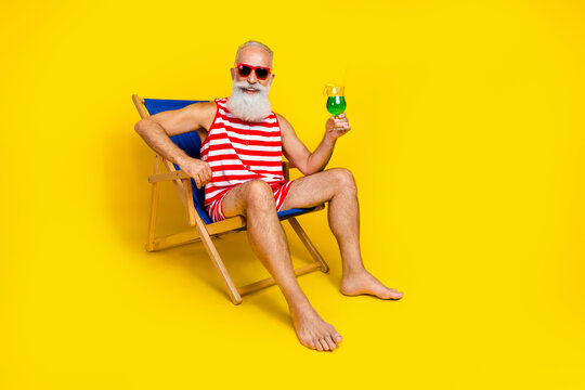 Full body photo of handsome cheerful person chill lounger hold drink glass empty space isolated on yellow color background