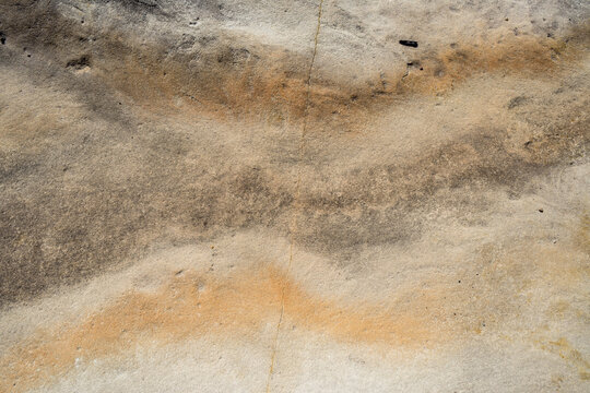 Close up of rock with cream, orange and brown wavey pattern and crack through middle