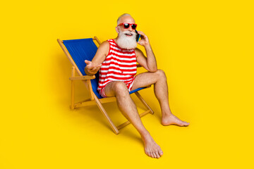 Full body photo of elderly person sit lounger speak chatting telephone isolated on yellow color...