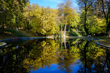 Landscape with many large green and yellow trees near the lake in Kiseleff Park in Bucharest, Romania,  in a sunny autumn day. - Powered by Adobe