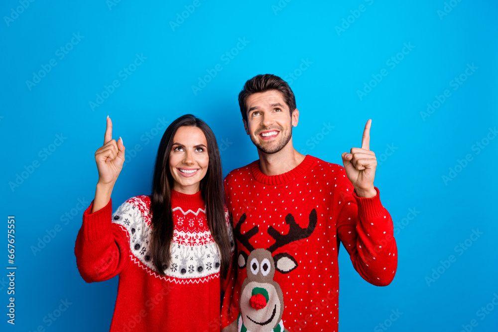 Wall mural photo portrait of lovely young spouses point look up empty space dressed x-mas ornament red sweaters