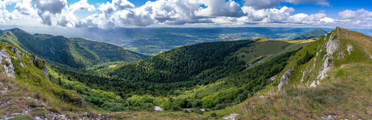 Naklejka na ściany i meble Grand Colombier, France - 08 31 2021: Grand Colombier Pass. View of the Col Du Grand Colombier, the forest, the road, the Lake Bourget and the mountains ridge behind.