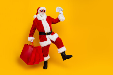 Fototapeta na wymiar Full length photo of saint nicholas man holding banknotes holding shopping bags he spend weekend money isolated on yellow color background
