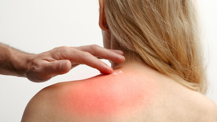 Man applying pain relieving cream, gel on woman's neck on white background. Pain relief and health care concept.