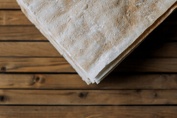 Many layers of dry dough prepared for a cake on a wooden background. Close-up food photography, cooking concept.