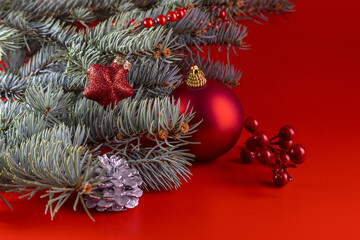 Fir branches and Christmas decorations on a red background. Copy space