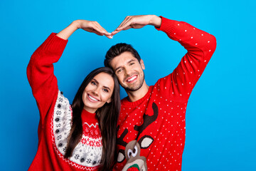 Photo portrait of lovely young spouses showing hands shape heart dressed x-mas ornament red sweaters isolated on blue color background