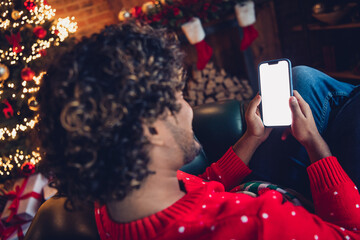 Rear view photo of young curly hair man holding phone when chill at home winter xmas holiday lying...