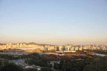 Fototapeta na wymiar SEOUL, SOUTH KOREA - OCTOBER 24, 2022: Colourful foliage trees in Autumn with various buildings in the afternoon and blue sky.