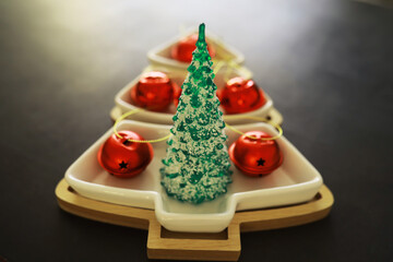 Christmas background. Dish in the shape of a Christmas tree with balls decorations on the table.