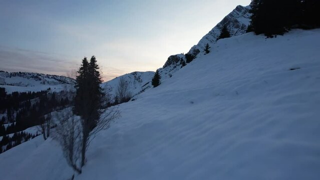 Drone slider forward towards the halo of the sunset hidden behind the peak of the snowy mountain