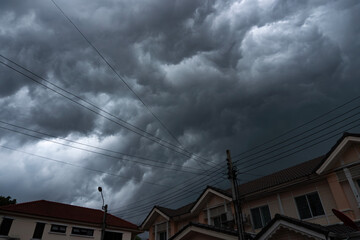 A storm is starting with black clouds over the village, climate change.