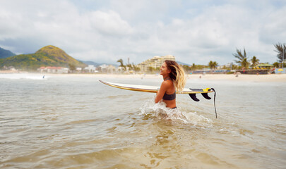 happy caucasian surfer woman walking in the water with a surfboard 