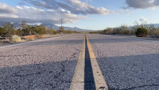 Road marking for an endless highway that crosses the famous Mojave Desert, towards Las Vegas in Nevada with desert mountains and a blue sky and a hot day.