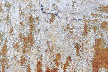 The texture of a cracked layer of paint on a metal sheet with rust showing through.