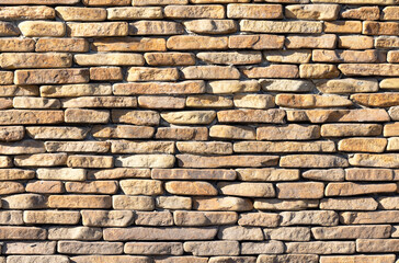 The wall is lined with old sandstone river cobblestones in the sun.