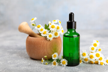 Fototapeta na wymiar Glass bottle with chamomile essential oil on an old wooden background. Chamomile flowers, close up. Aromatherapy, spa and herbal medicine ingredients. Beauty concept.Copy space. Natural cosmetic