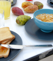 Continental breakfast - toast, orange juice and  prickly pears on white table.