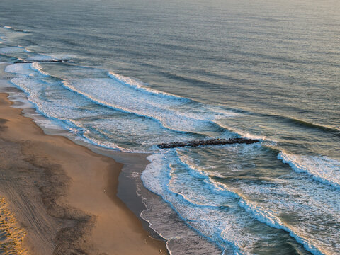 Ocean waves along the beach with a rocky jetty