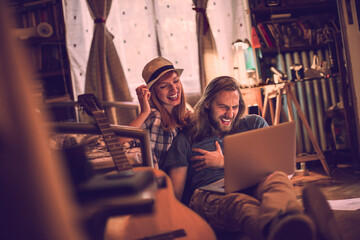 Happy young couple laughing with a laptop on the bedroom floor at home