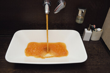 The domestic bathroom has a rusty faucet that dispenses dirty water. Rusty liquid flows...