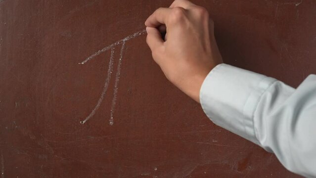 Textured brown chalkboard background. Male hand writing a Pi value, number 3,14 on the board with a piece of white chalk in close up.