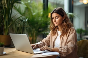 Woman Sitting at Table Working on Laptop