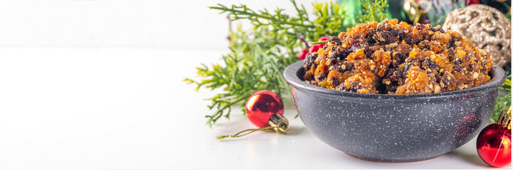 Homemade Christmas sweet mincemeat bowl, dried fruit mince meat for traditional winter mince pies with cinnamon sticks, anise, with festive decorations and christmas tree branches