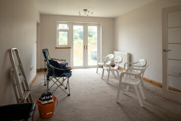 Empty lounge on moving in day, with basic plastic chairs