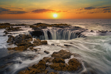 Water rushes into Thor's Well in Pacific Ocean at sunset in Oregon.