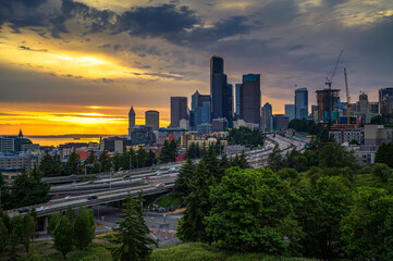 Dramatic sunset over the Seattle downtown skyline, with traffic on the I-5 and I-90 freeway...