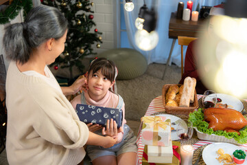 Little girl receives gifts from her family members during Christmas dinner at home.