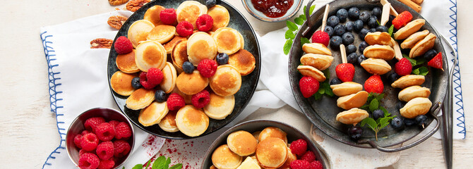 Delicious pancakes with blueberry, strawberry and raspberry. Sweet and tasty breakfast on ligt background
