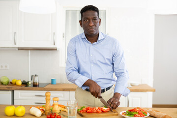 Man prepares a vegetable salad for dinner in a home kitchen