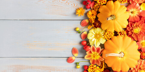 Composition of orange pumpkins, dahlia flowers, marigolds and hawthorn berries on a blue wooden table with a place for text. Greeting card. Nature concept