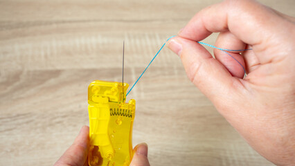 Woman threading needle with threader