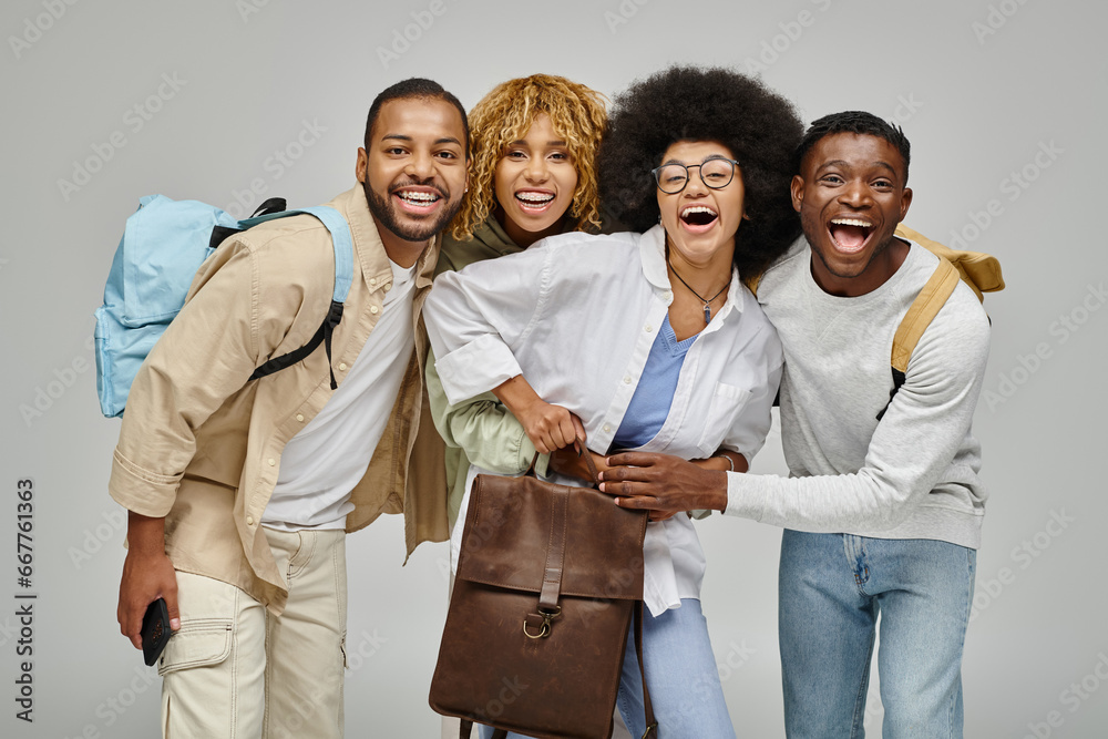 Wall mural jolly young friends in casual attires smiling at camera and holding backpacks, student lifestyle