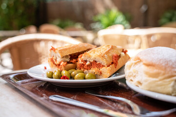 Iberian sobrasada sandwich served with olives on the terrace of a restaurant