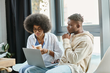 concentrated friends in casual outfits with coffee cup in hands working on laptop, business concept