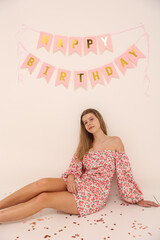 birthday photo of a young girl on a white background. short pink party dress. a crown on the...