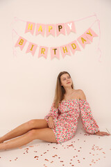 Obraz na płótnie Canvas birthday photo of a young girl on a white background. short pink party dress. a crown on the birthday girl's head. pink inscription happy birthday. The girl is 16 years old. fashionable young woman