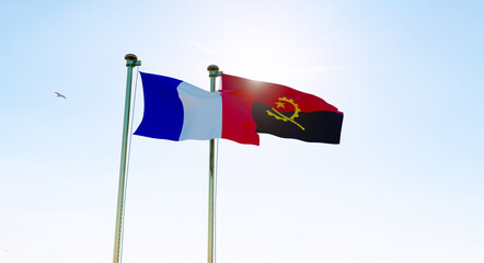 Angola and France flags waving against a blue sky background. 
