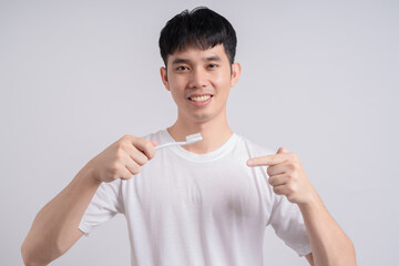 Young handsome man brushing his teeth over isolated background smiling a lot