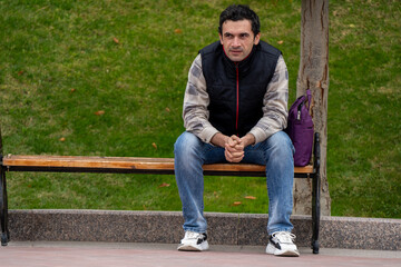 Obraz premium Armenian man, different emotional face actions, in the outdoor, the cold temperature, with the jacket, outdoor sitting in a table near a tree