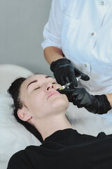 woman enlarges her lips with hyaluronic acid from a cosmetologist. Injection cosmetology. Lip...