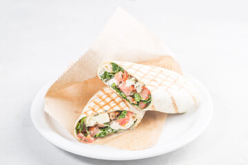 Pita roll with salmon and vegetables filling. Shawarma in pita bread stuffed with vegetables and fish.