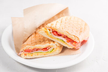 Sandwich with ham, cheese and tomatoes. Sandwich with sauce in a grilled white bun.